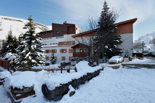 un edificio con neve di fronte a un edificio di Vacancéole - Résidence L'Edelweiss a Les Deux Alpes