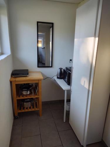 uma pequena cozinha com uma mesa e um espelho em Commuter room for one or two people em Munkebo
