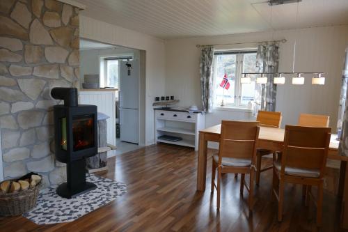 sala de estar con chimenea, mesa y fogones en Koselig Hytte i Nykvåg, en Nykvåg