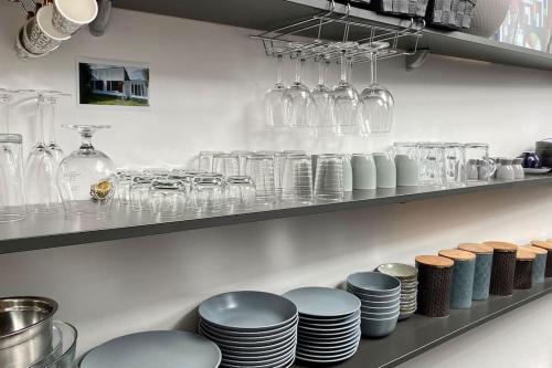 une étagère avec des assiettes et des verres dans l'établissement La Baie Latitude, gîte proche mer avec jardin, au Crotoy