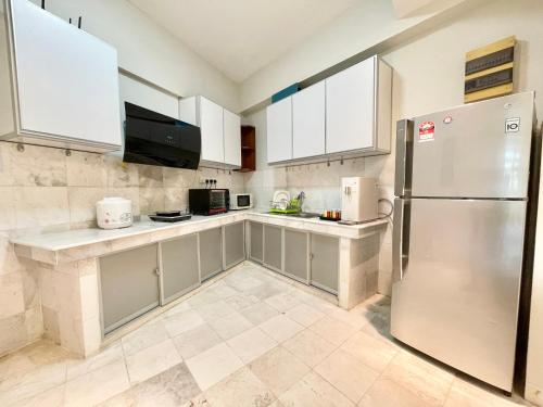 a kitchen with white cabinets and a stainless steel refrigerator at Century Suria Aparment Langkawi by Zervin in Kuah