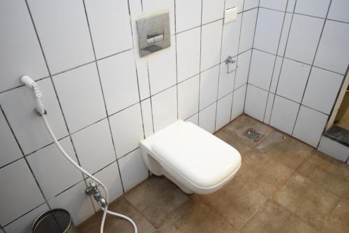 a white toilet in a bathroom with a shower at Lakshmi Vilas in Mannārgudi
