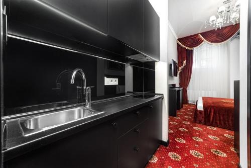 Arcadia Plaza Apartments في أوديسا: مطبخ مع حوض وسجادة حمراء