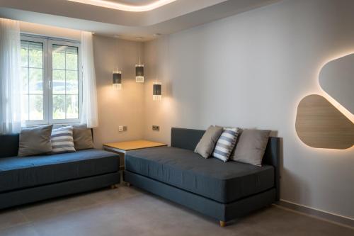a living room with two blue couches and a window at Evdokia Suites in Gouves