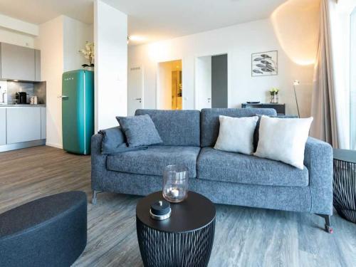 Una sala de estar con un sofá azul y una mesa. en Hafenspitze App 28, en Wismar