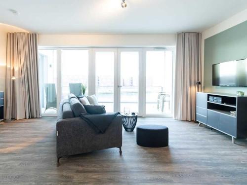Una sala de estar con un sofá y un televisor. en Hafenspitze App 28, en Wismar
