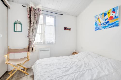 een witte slaapkamer met een bed en een stoel bij Appartement SAINT CLAIR proche du Port in Saint-Martin-de-Ré