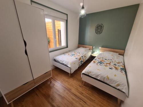 een slaapkamer met 2 bedden en een raam bij Le calme de la nature à 8 minutes des plages in Sémussac