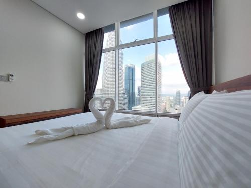a bedroom with a white bed with a large window at Sky Suites with KLCC Twin Tower View by iRent365 in Kuala Lumpur