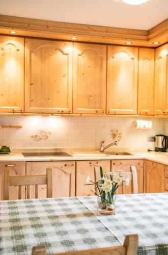 a kitchen with wooden cabinets and a table with flowers at Chalet Sisters in Livigno