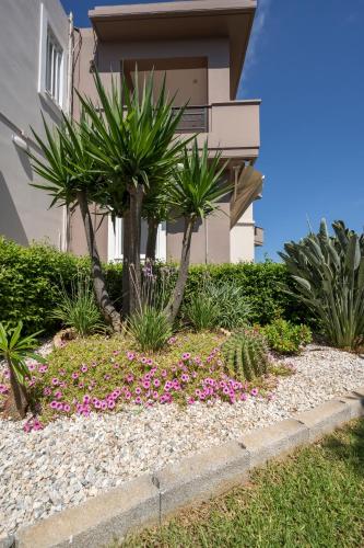 a house with palm trees and flowers in front of it at Tholos Apartments in Chania Town