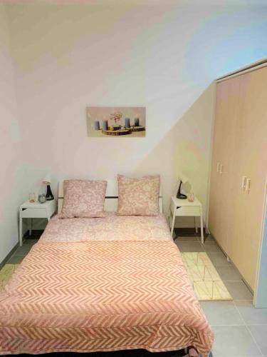 a bedroom with a bed with pink sheets and two tables at Studio avec jardin clos et wifi a Dijon in Dijon