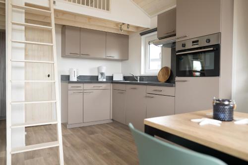 a kitchen with white cabinets and a wooden table at Chalet bis 4 Personen ohne Hund - a61158 in Norden