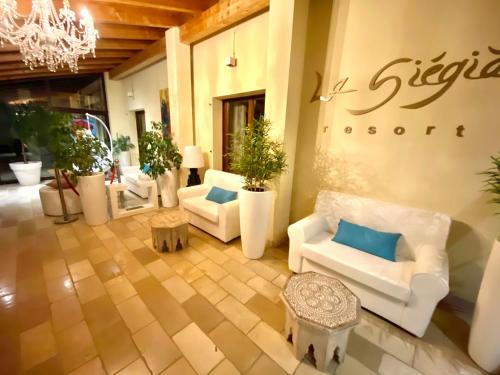 a lobby with white couches and potted plants at La Siègià Resort spa in Massa Marittima