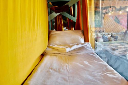 een bed in een kamer met een gele muur bij Nomad Hostel in Nimrod