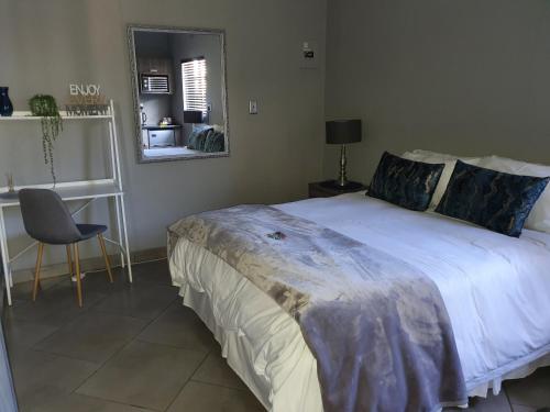 a bedroom with a bed and a mirror and a chair at A’ La Maison Guesthouse in Kimberley