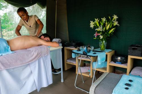 un hombre acostado en una cama en una habitación con una mujer en Honeyguide Tented Safari Camps - Mantobeni en Manyeleti Game Reserve