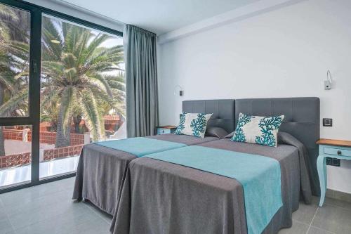a bedroom with two beds and a palm tree at Two Dreams Luxury Villa in Corralejo