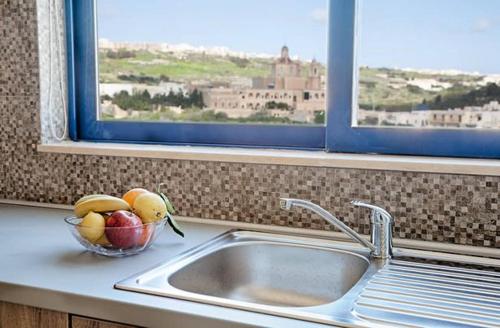 uma tigela de fruta num balcão de cozinha ao lado de um lavatório em Ir-Rixa Holiday Penthouse em Ghajnsielem