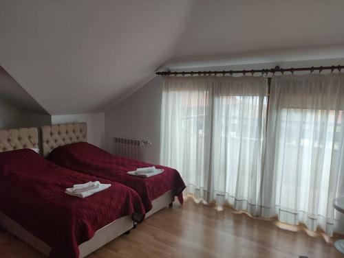 a bedroom with a bed with red sheets and windows at Guest House Ela in Bansko