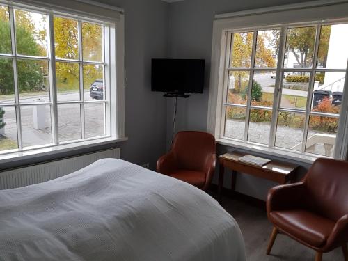 a bedroom with two chairs and a bed and windows at FE Gisting in Akureyri