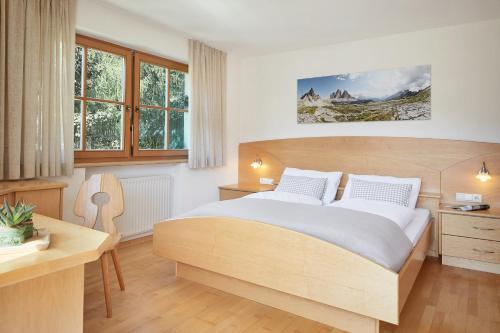 um quarto com uma cama, uma secretária e janelas em daHoam Appartamenti em Rasùn di Sotto
