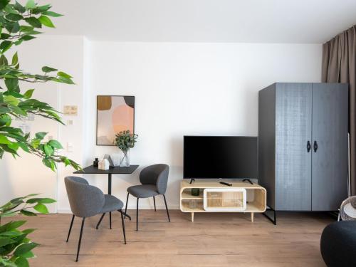 a living room with a table and a tv and a cabinet at Limehome Frankfurt Gutleutstraße - Digital Access in Frankfurt/Main