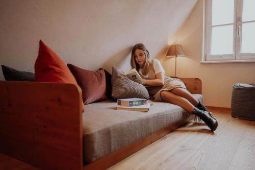 a woman sitting on a bed looking at a tablet at Altstadtmittehotel Sonne in Dinkelsbühl