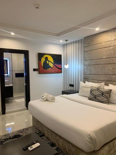 a bedroom with a large white bed and a bathroom at Gordonsville Escape Boutique Hotel in Port Harcourt