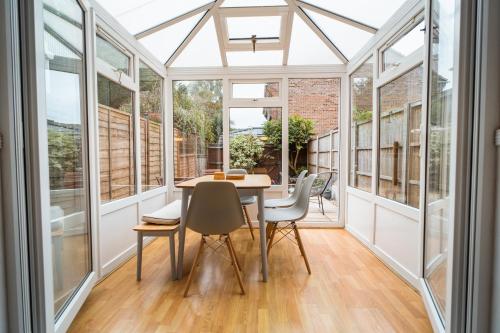 - une véranda avec une table et des chaises dans une chambre dotée de fenêtres dans l'établissement Beautiful Town House with Private Garden and Patio, à Canford Magna
