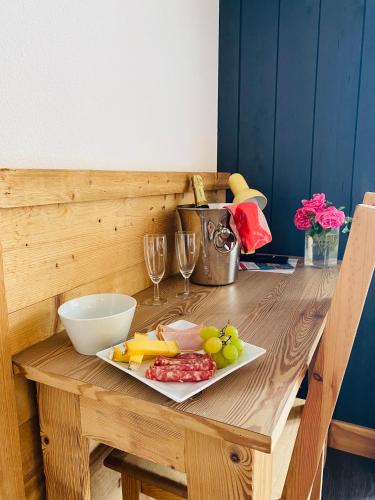 a wooden table with a plate of food and wine glasses at Les Reflets du Lac in Gérardmer