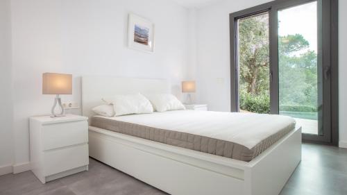 a white bedroom with a large bed and a window at VILLA MEXIC in Llafranc