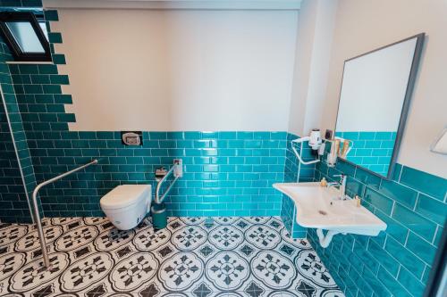 a blue tiled bathroom with a toilet and a sink at Fortunella Suites in Finike