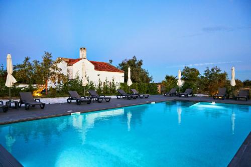 a large swimming pool with chairs and umbrellas at EcoVillas Escudeira in Reguengos de Monsaraz