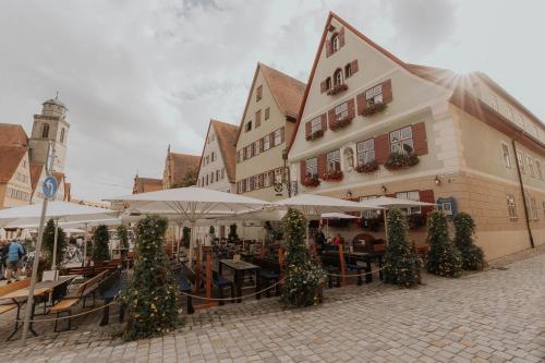 ein Gebäude mit Tischen und Sonnenschirmen im Innenhof in der Unterkunft Hotel Gasthaus zur Sonne in Dinkelsbühl