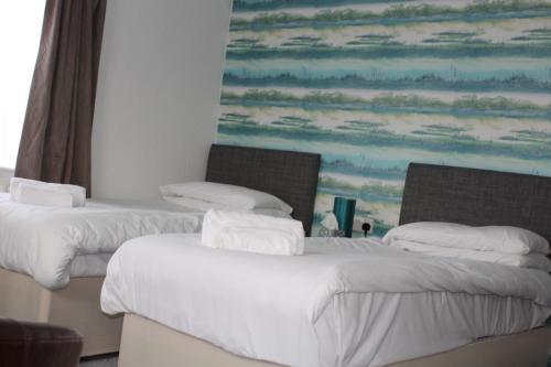two beds in a room with a painting on the wall at Stukeleys Hotel in Great Stukeley