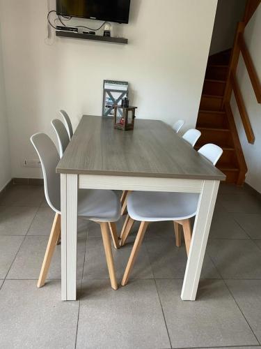 une table en bois avec des chaises blanches et une télévision dans l'établissement Equihen Plage Maison 83, à Équihen-Plage