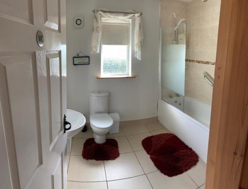 a bathroom with a toilet and a tub and a sink at Causeway Coast Country Cottage, Pet-friendly in Ballycastle