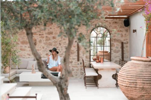 a woman in a hat sitting on a couch in a courtyard at Inotropes Boutique Suites - Adults Only in Archanes