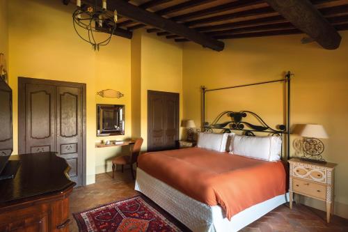 a bedroom with a large bed and a desk at Castello di Casole, A Belmond Hotel, Tuscany in Casole dʼElsa