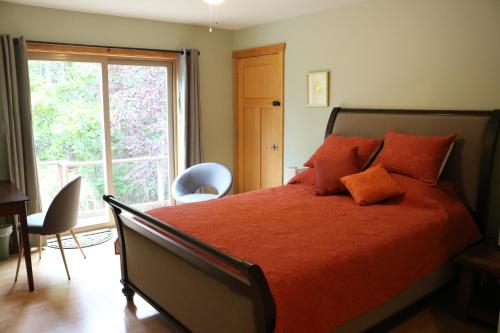 um quarto com uma grande cama vermelha e uma janela em Five Elements Lodge B&B with Outdoor Spa em Fernwood