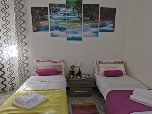 2 Betten in einem Zimmer mit Gemälden an der Wand in der Unterkunft Bnbook-L'appartamento di Gio' in Rho