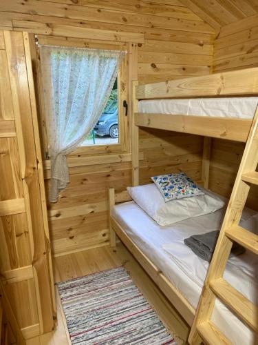 a bedroom with two bunk beds and a window at Dubryk Domki na Kaszubach in Stara Kiszewa