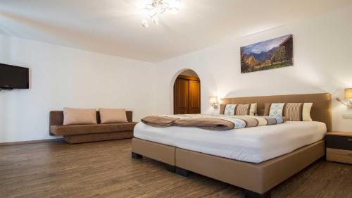 1 dormitorio con 1 cama grande y 1 sofá en Pension Riese, en Neustift im Stubaital