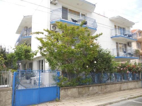 un edificio con cancelli blu e un albero di fronte ad esso di "Aхтополис" - подсигурено безплатно паркиране ad Ahtopol