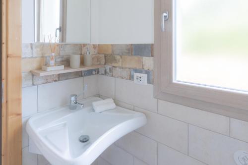 a white bathroom with a sink and a mirror at Su Cappeddu Agriturismo in San Giorgio