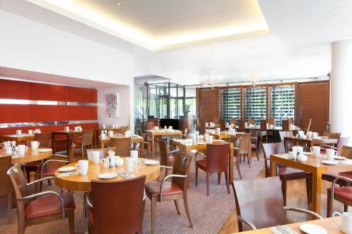 una sala da pranzo con tavoli e sedie in legno di Crowne Plaza London - Docklands, an IHG Hotel a Londra