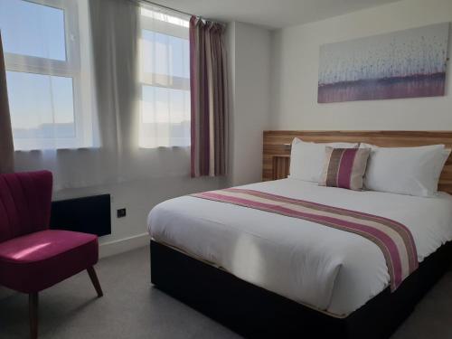 a bedroom with a large bed and a red chair at Escape Hotel in Barrow in Furness