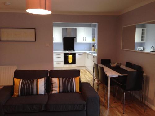 a living room with a couch and a table and a kitchen at Flat Three, 212 Eaglesham Road, East Kilbride, Glasgow in East Kilbride