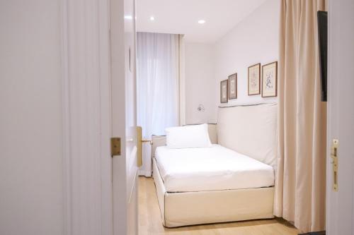 a white bedroom with a white bed and a window at Relais Donna Lucrezia in Rome